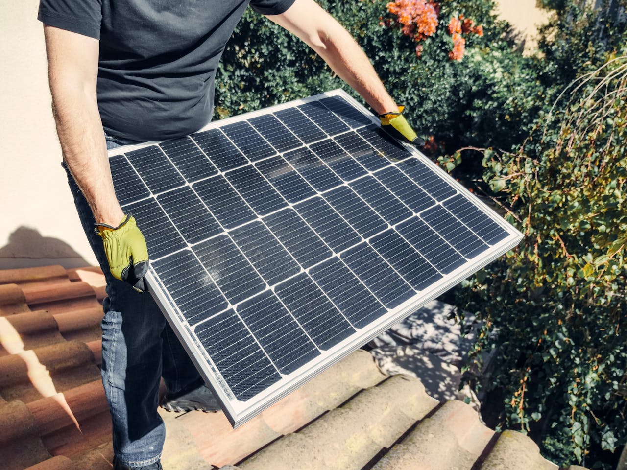 services-img A worker in gloves installs a solar panel on a tiled rooftop, promoting renewable energy.